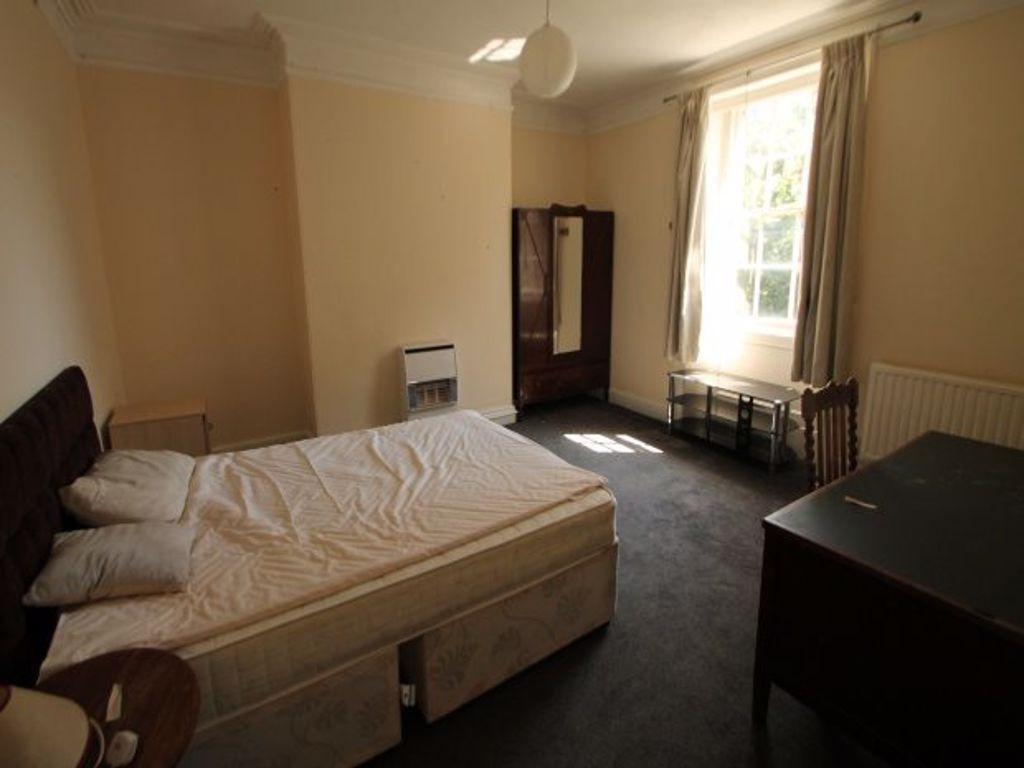 A cozy bedroom with a large window that lets in...