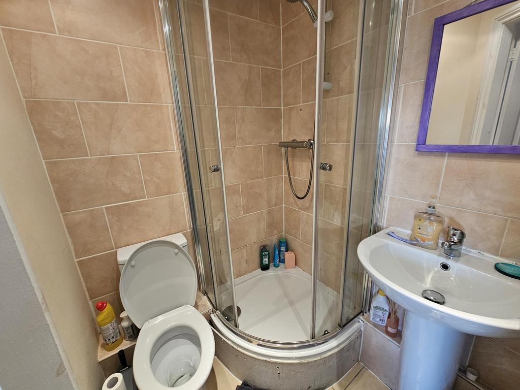 Compact tiled bathroom with a corner shower enc...