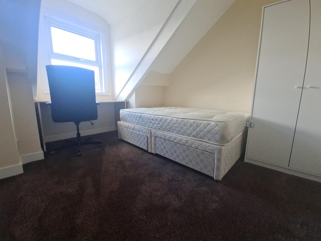 A well-lit, tidy bedroom featuring a single bed...