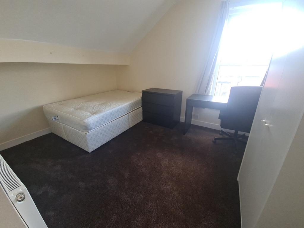A cozy bedroom featuring a single bed, a window...