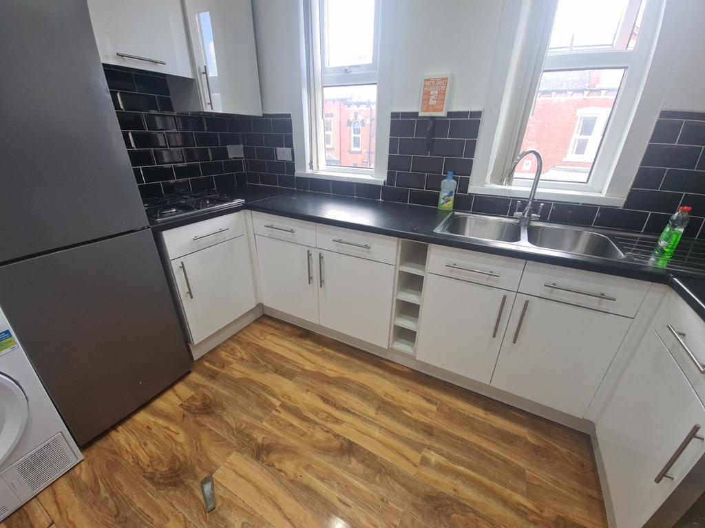 Modern kitchen area featuring clean white cabin...