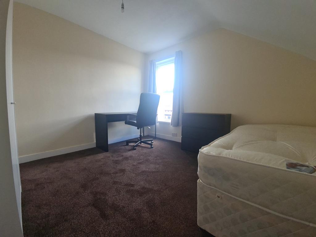 A spacious bedroom featuring a large bed, a des...