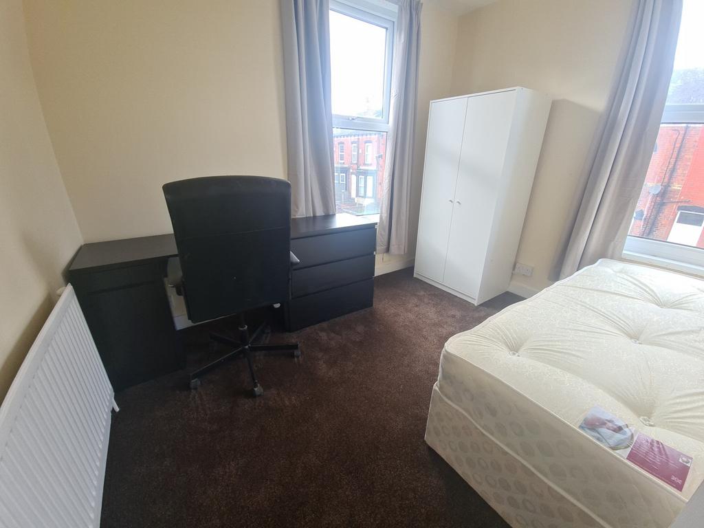 A tidy bedroom with a comfortable bed, a worksp...