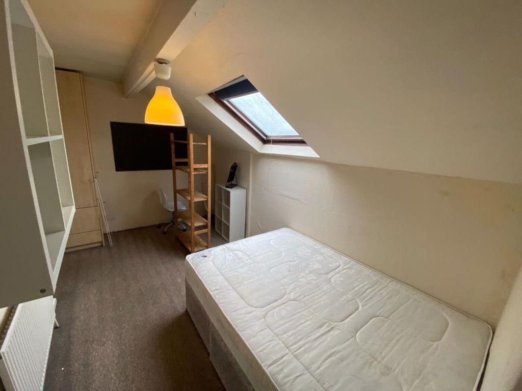 A cozy bedroom with a sloped ceiling and a skyl...