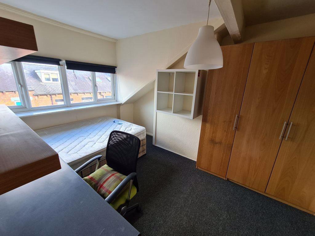 A cozy single bedroom featuring a large window ...