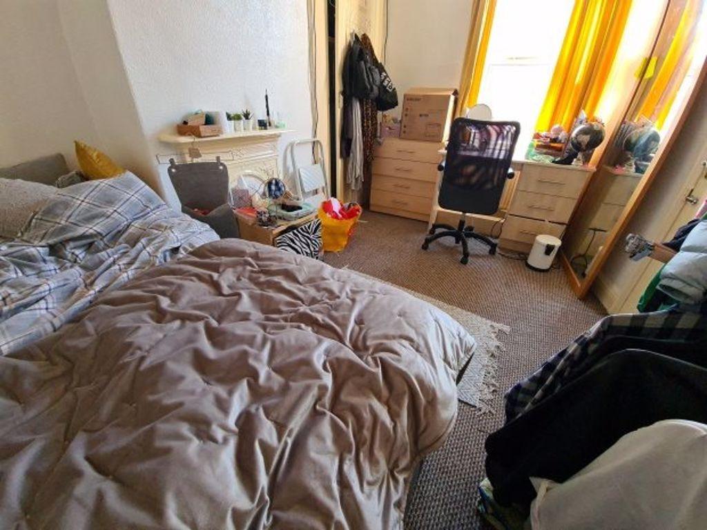A cozy bedroom with a neatly made bed, warm nat...