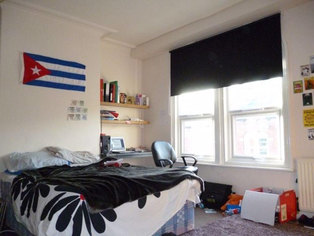 A cozy student bedroom featuring a bed with bed...