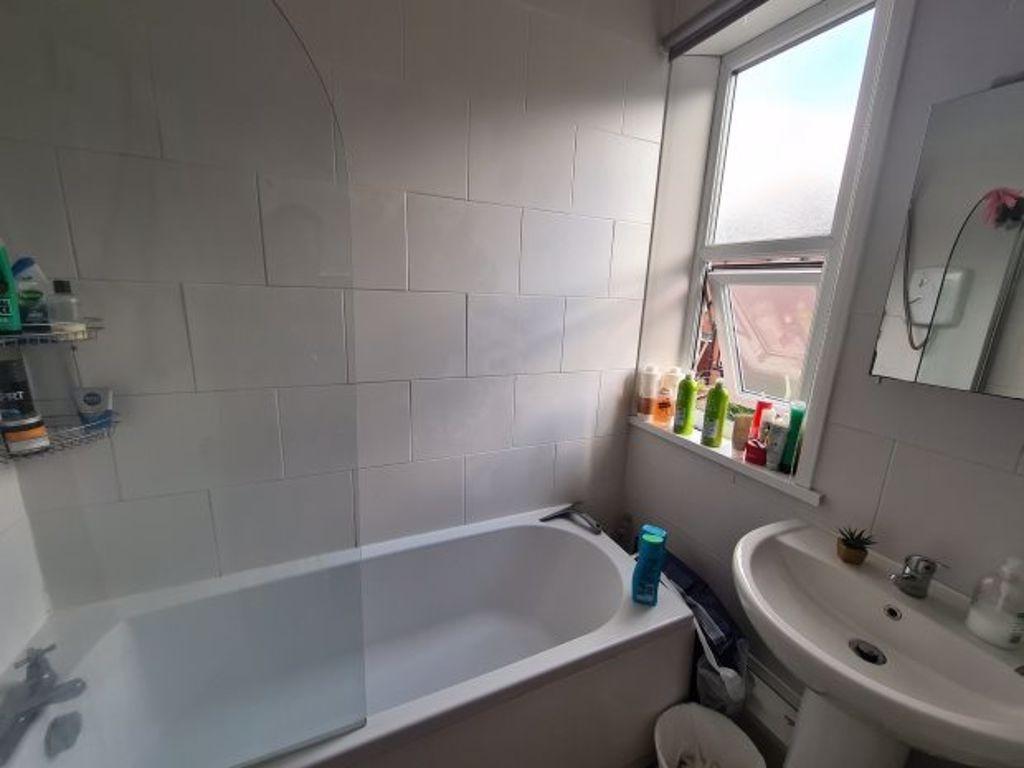 A clean and bright bathroom featuring a bathtub...