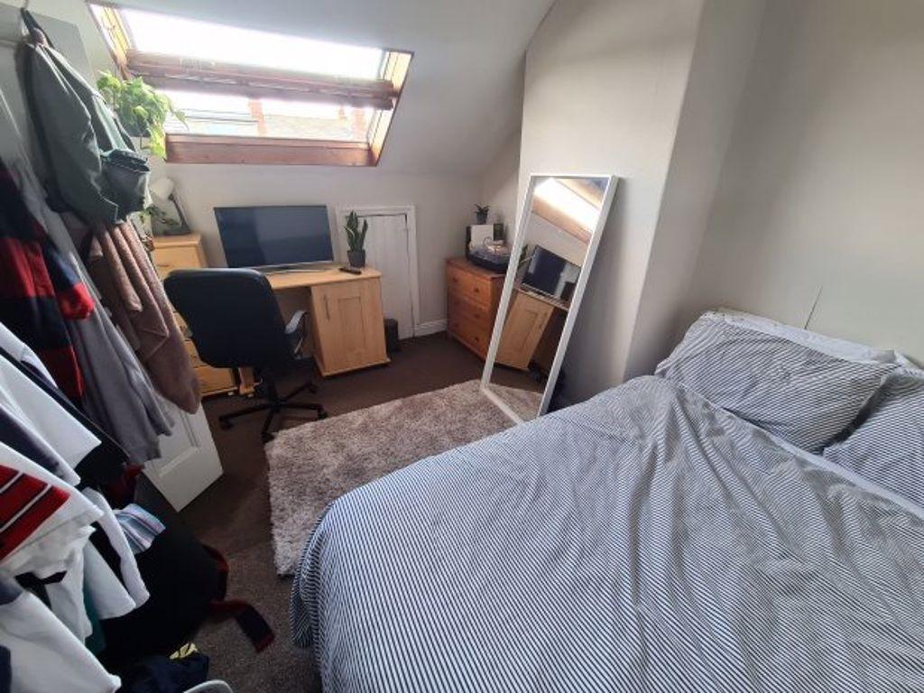 A cozy bedroom with a neatly made bed, a mirror...