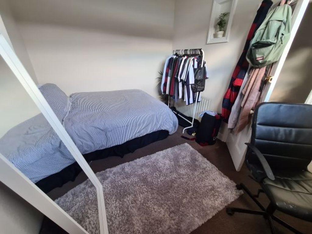 A cozy single bedroom featuring a bed, a window...