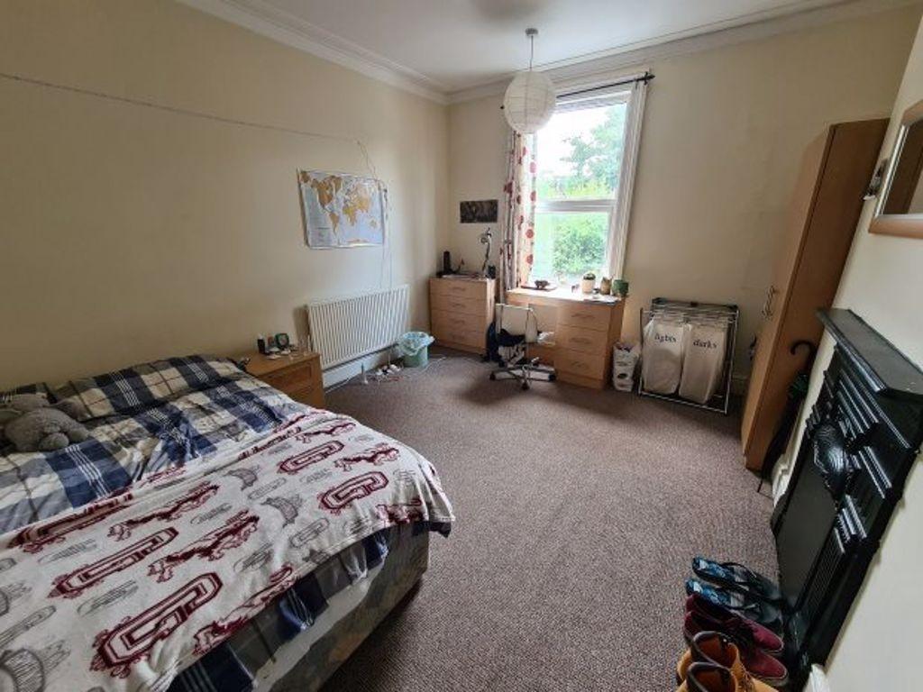 A cozy single bedroom featuring a bed, a window...