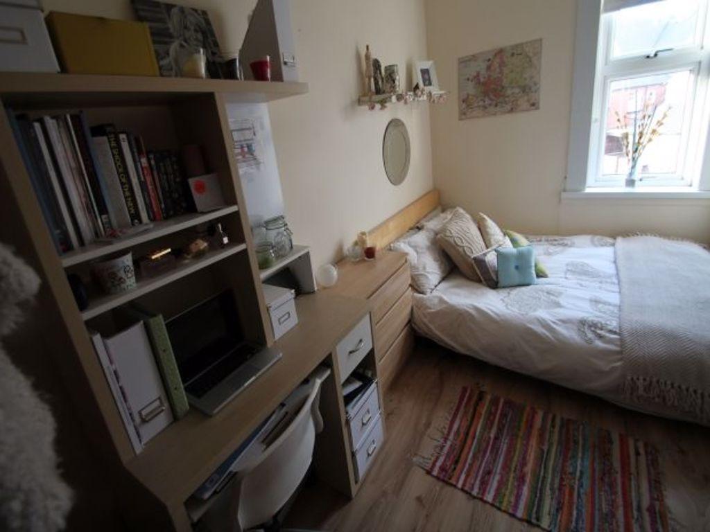 A cozy student bedroom featuring a bed and a bo...