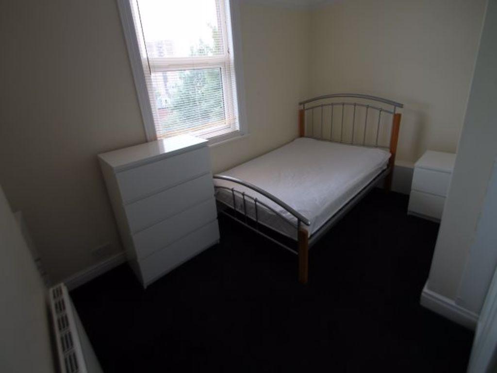 A tidy single bedroom featuring a simple bed, a...