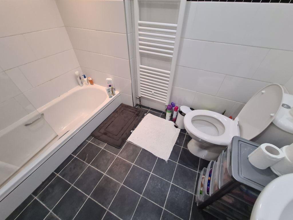 A clean and bright bathroom featuring a bathtub...