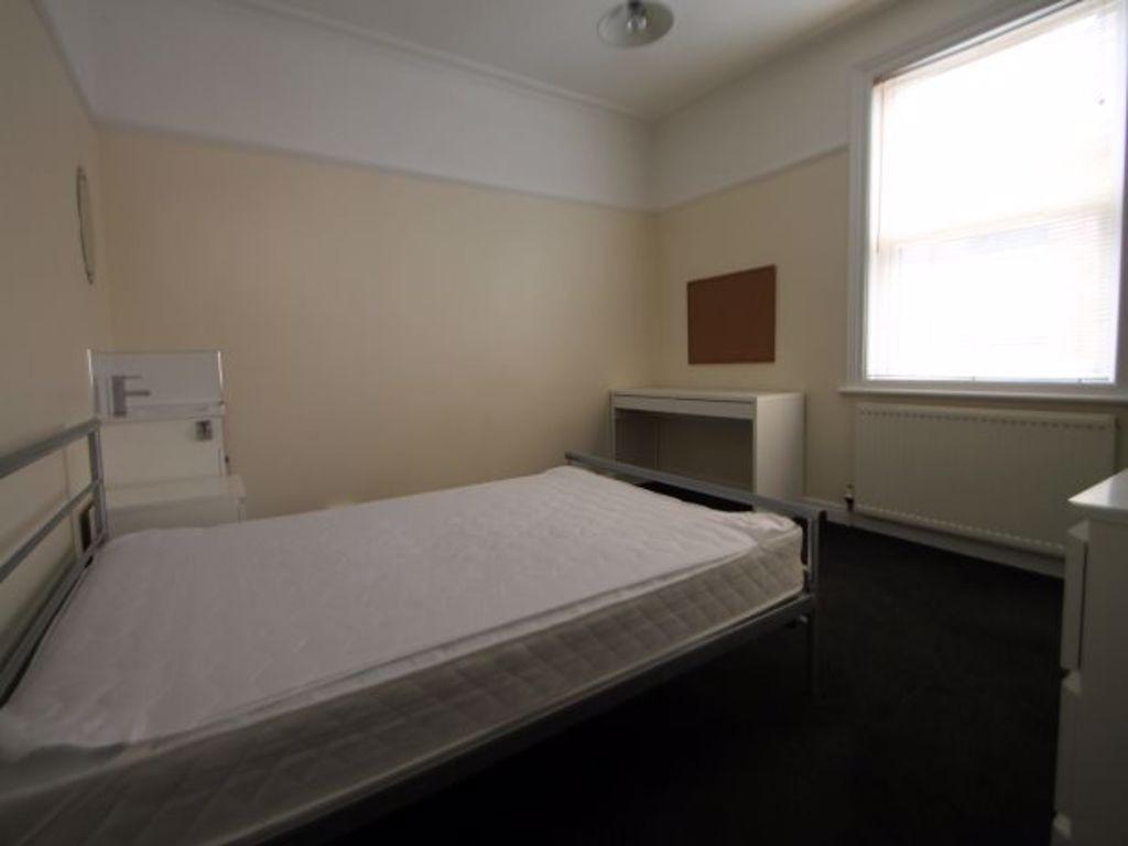 A simple and tidy bedroom featuring a comfortab...
