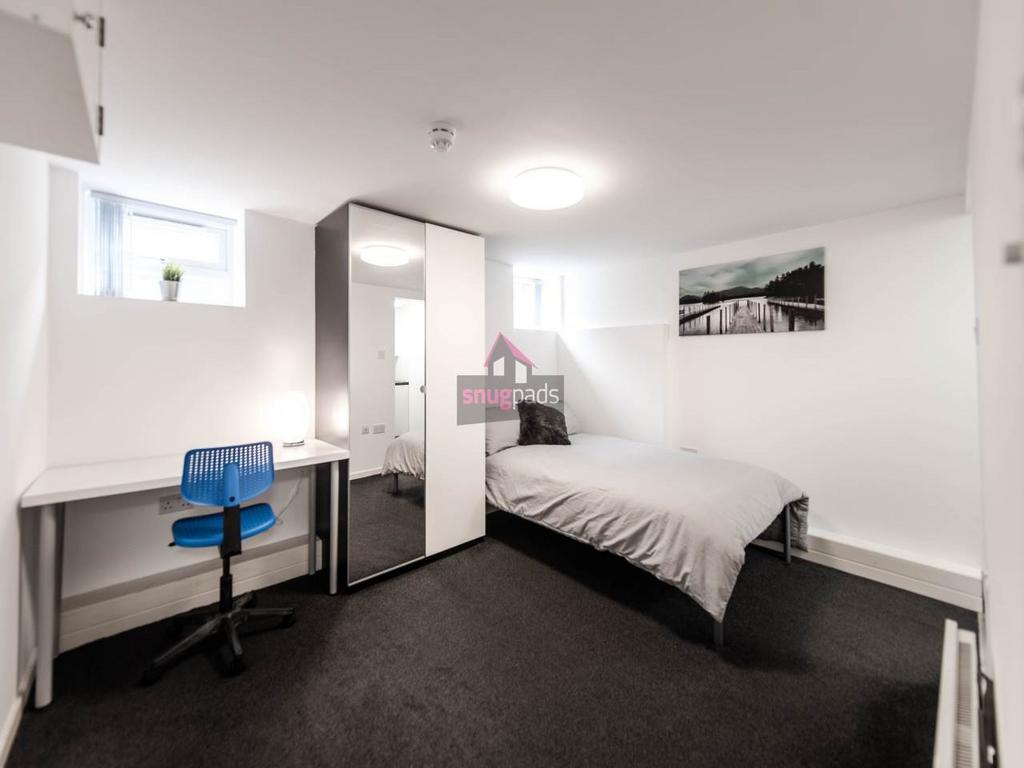 A bright and tidy student bedroom featuring a c...