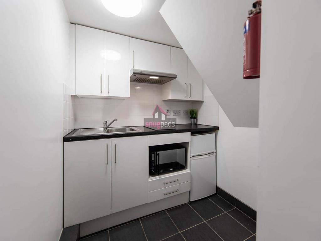 Modern compact kitchen with white cabinetry and...