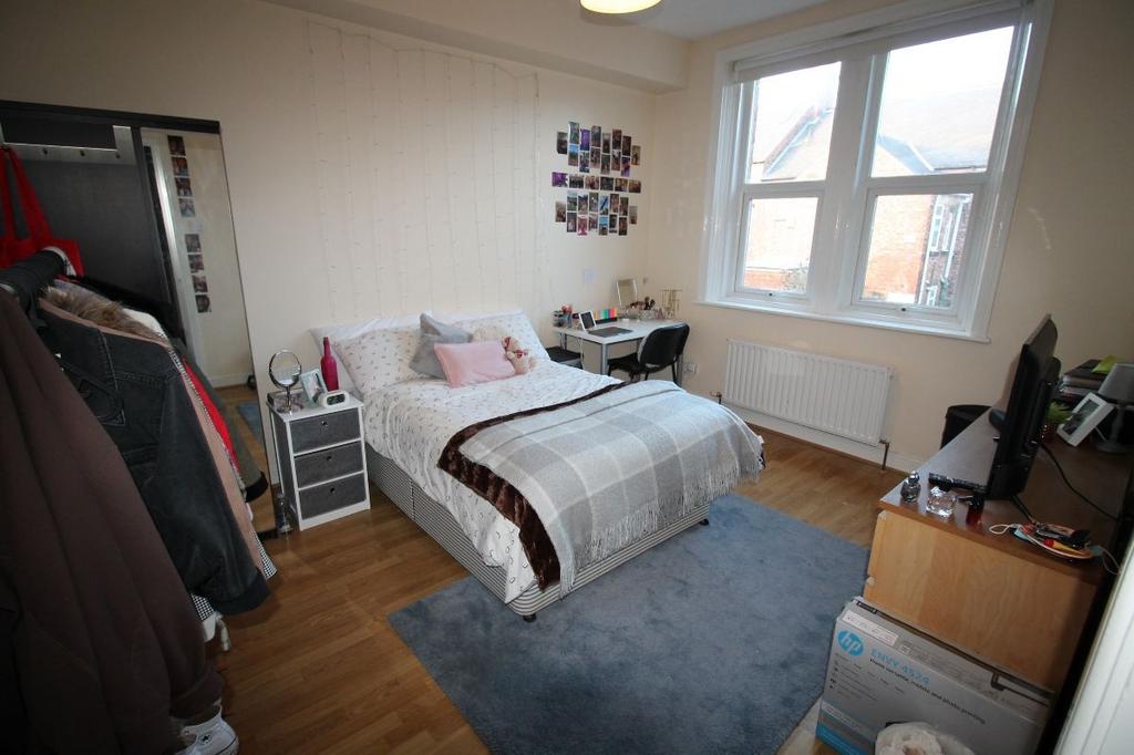 A well-lit, spacious master bedroom with a comf...