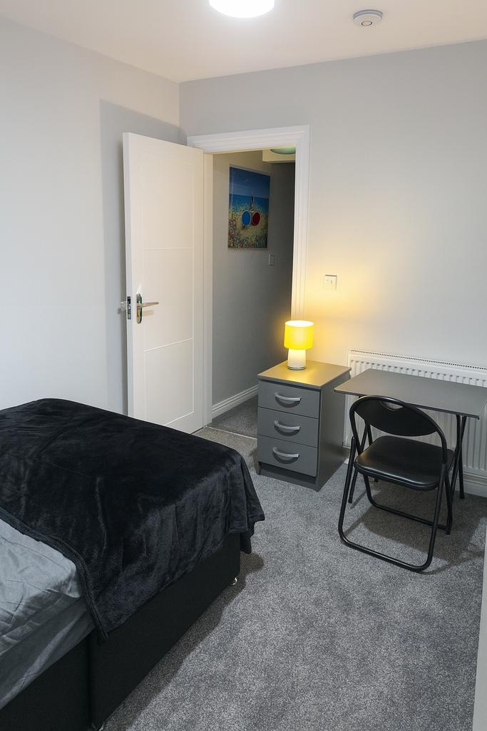 Neat single bedroom with a cosy bed, compact de...