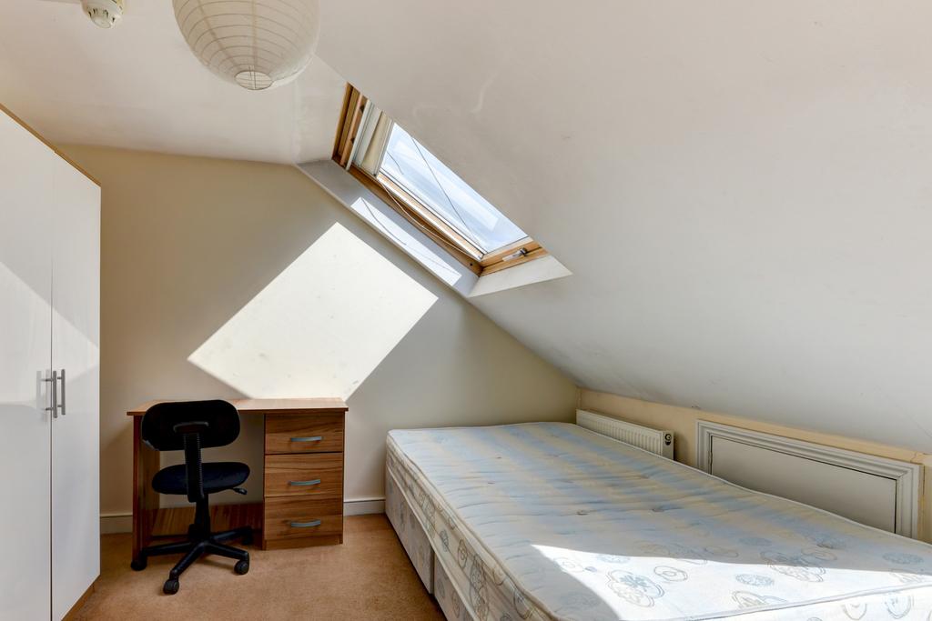 Bright attic bedroom with a sloped ceiling, sky...