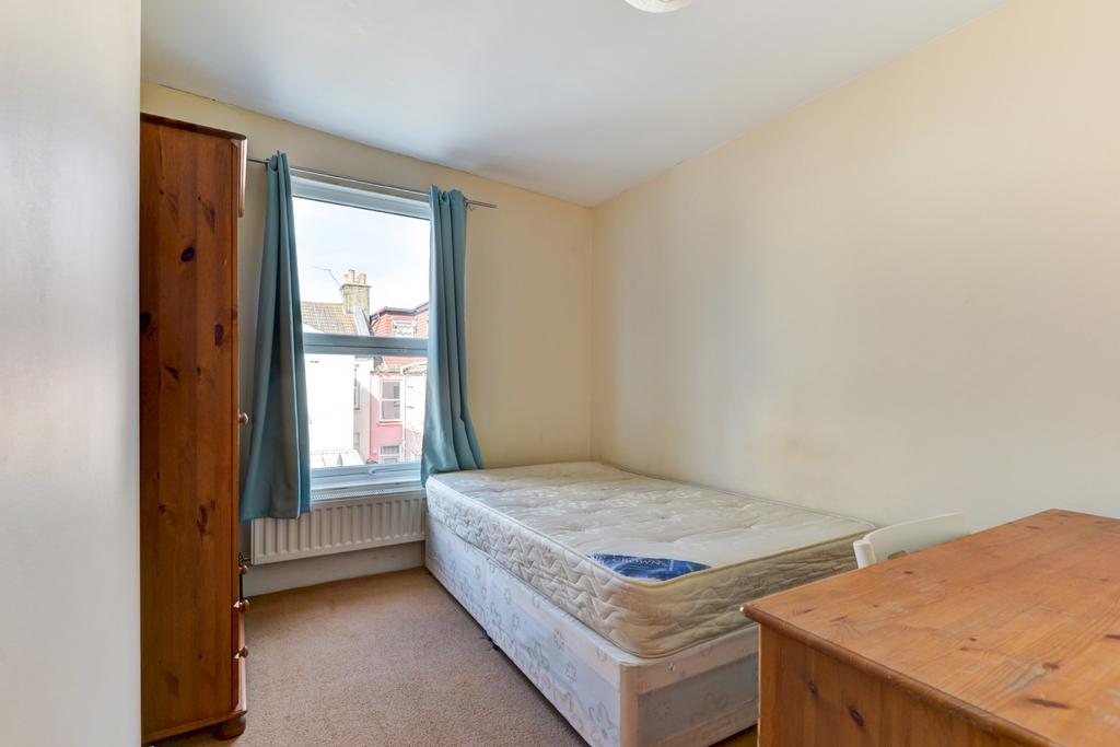 A cozy single bedroom featuring a bed and windo...