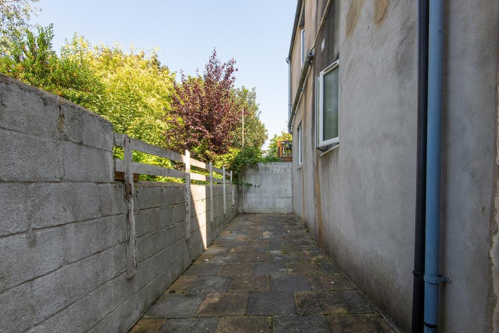 Narrow paved side path alongside the building w...
