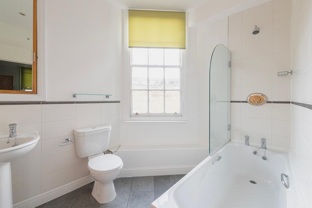A bright and clean bathroom featuring a bathtub...