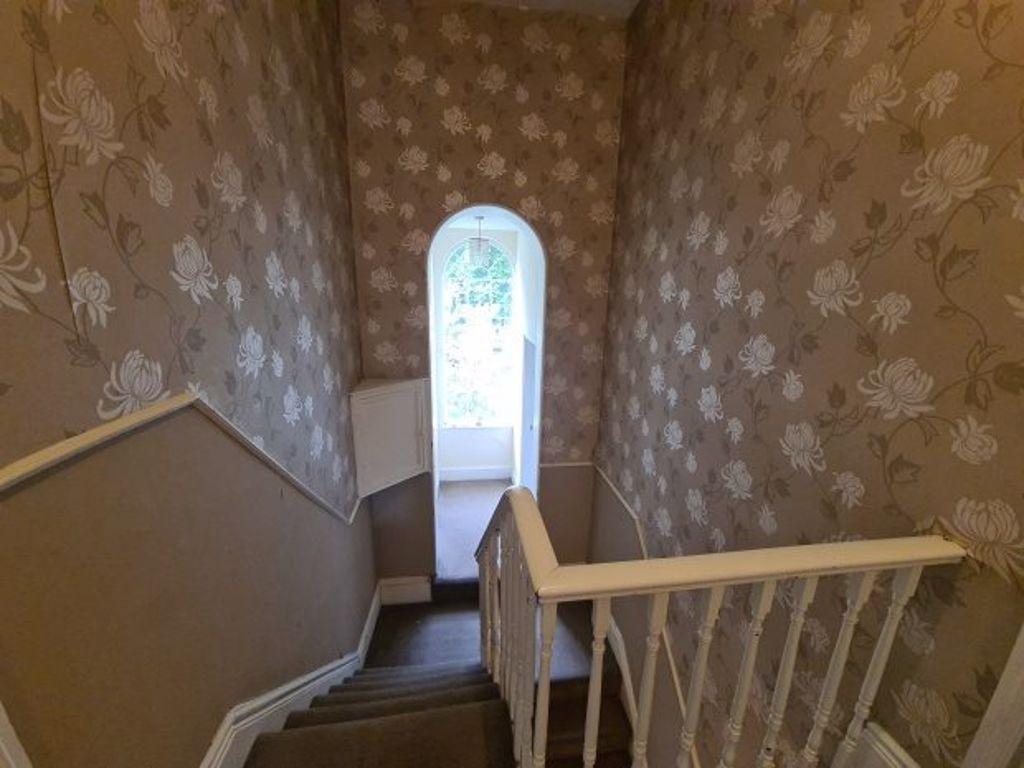 A quaint hallway with floral wallpaper and a wh...