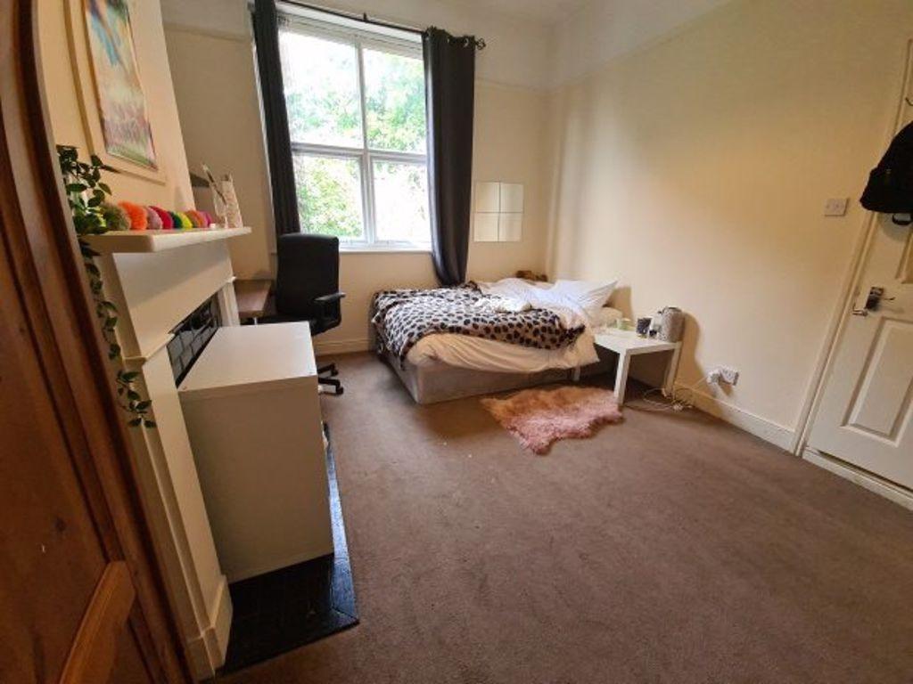 A cozy single bedroom featuring a large window ...