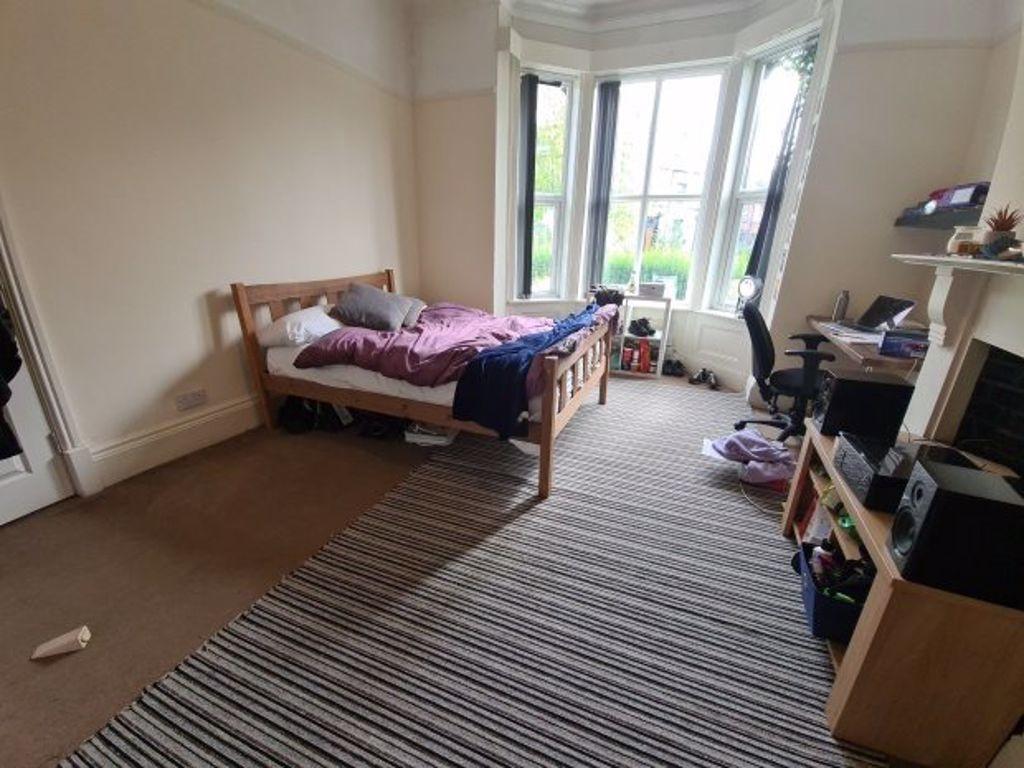 A cozy single bedroom with a large bay window a...