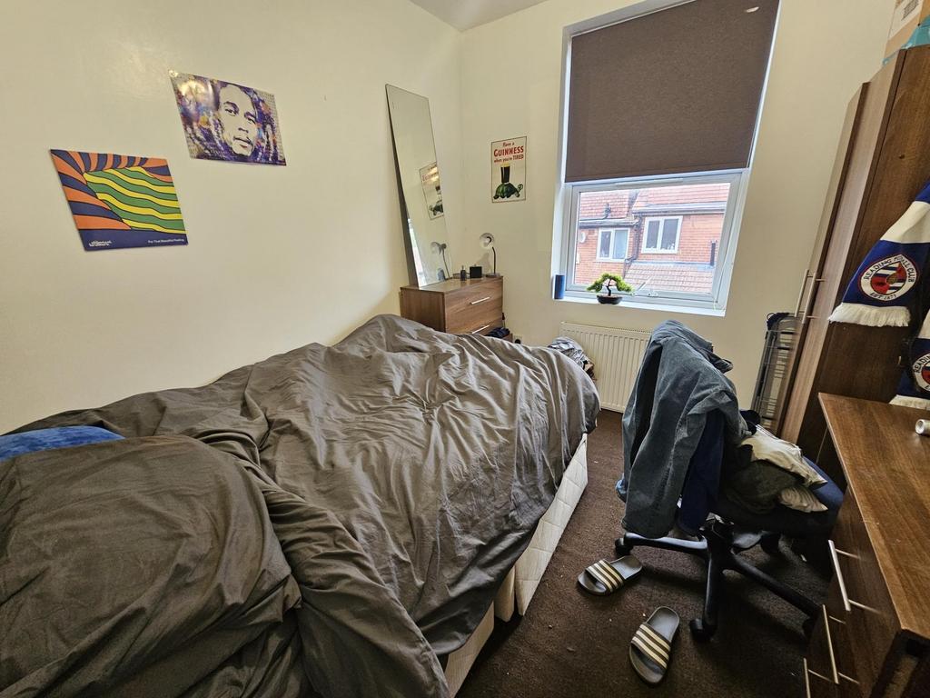 A cozy, modest bedroom with a single bed, a des...