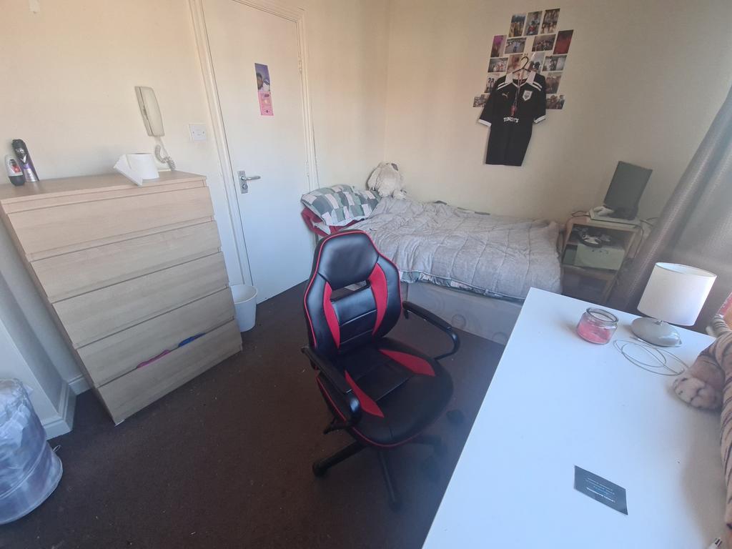 A cozy bedroom featuring a single bed, a desk, ...
