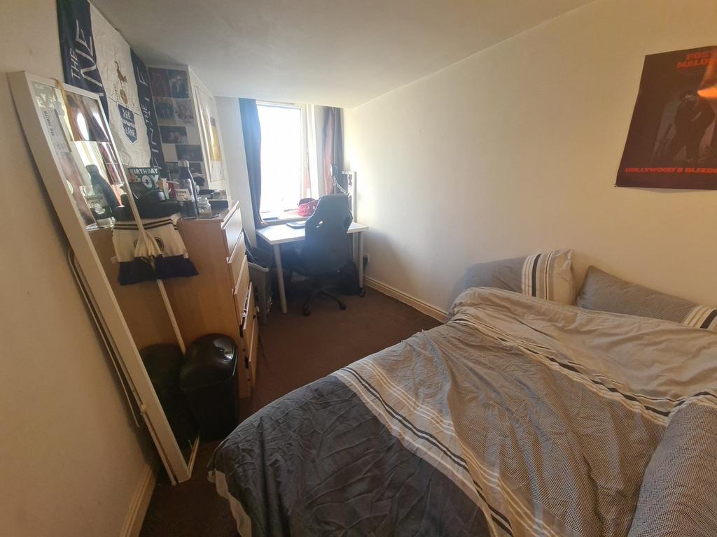 A cozy bedroom with a double bed, a desk, and a...