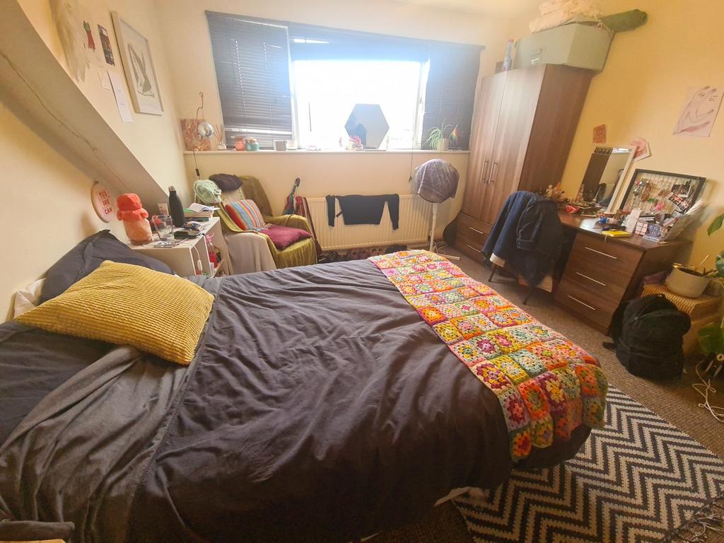 A cozy bedroom with a double bed covered in dar...