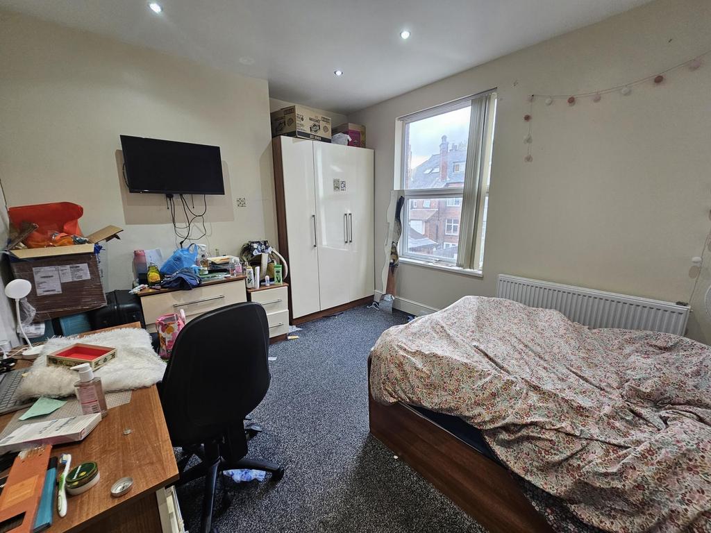 A cozy bedroom featuring a bed with a patterned...