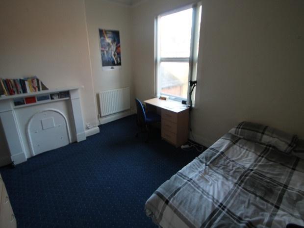 A cozy student bedroom featuring a bed near the...