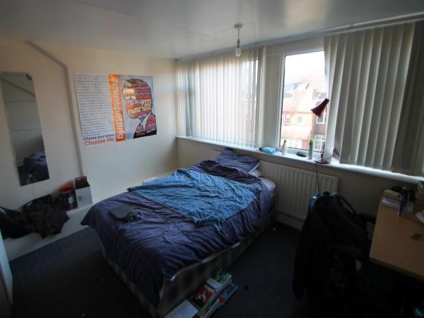A cozy bedroom featuring a neatly made bed near...