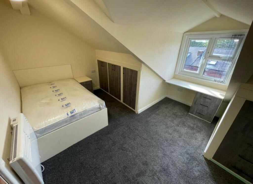 A cozy single bedroom featuring a bed, a window...