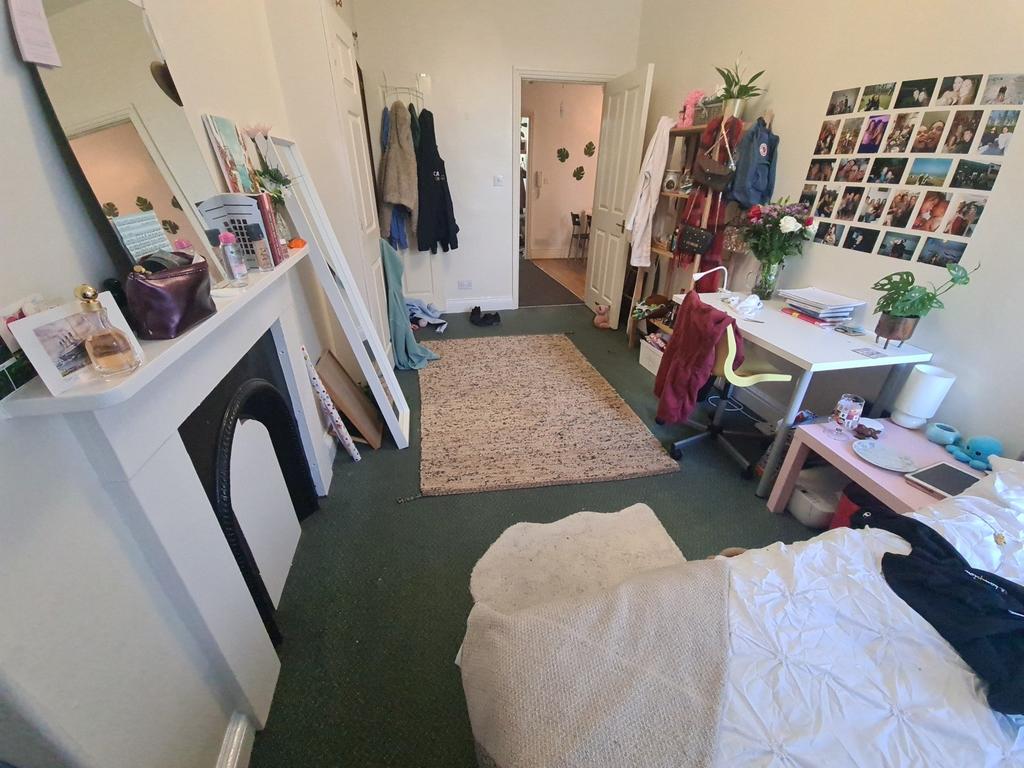 A cozy bedroom with a bed, personal belongings,...