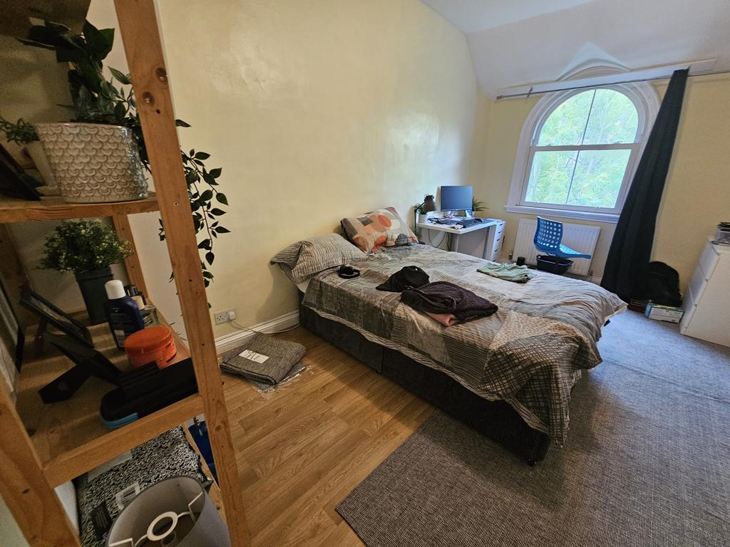 A cozy bedroom featuring a bed with bedding, a ...