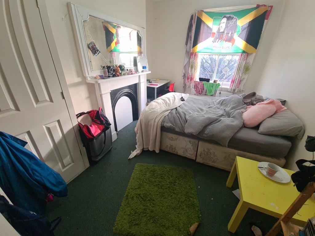 A cozy bedroom featuring a single bed positione...