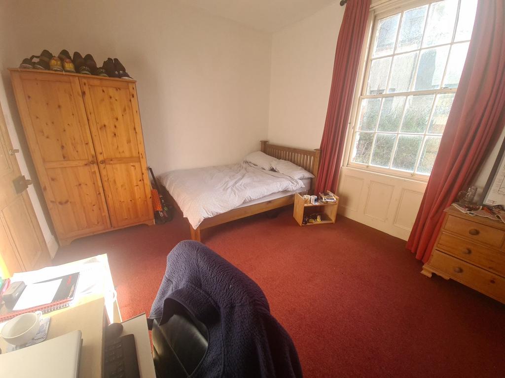 A cozy single bedroom featuring a comfortable b...