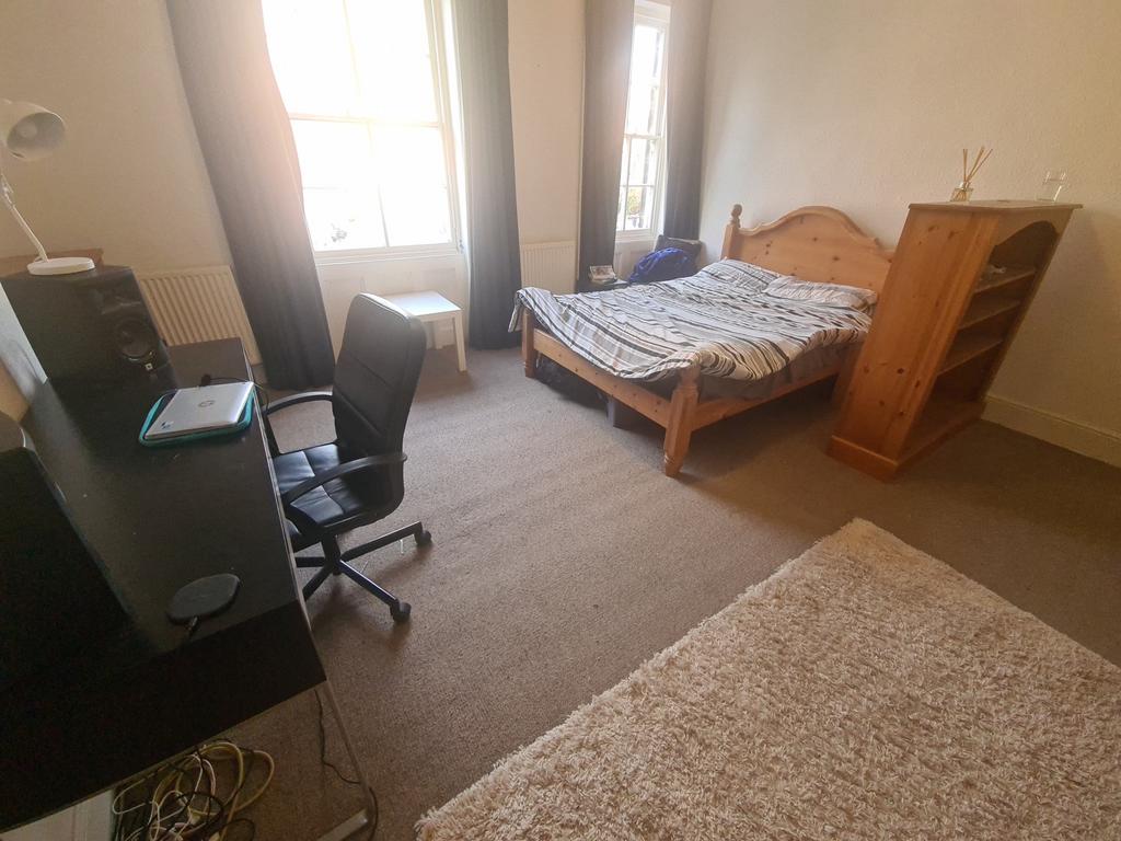 A cozy single bedroom featuring a wooden bed fr...