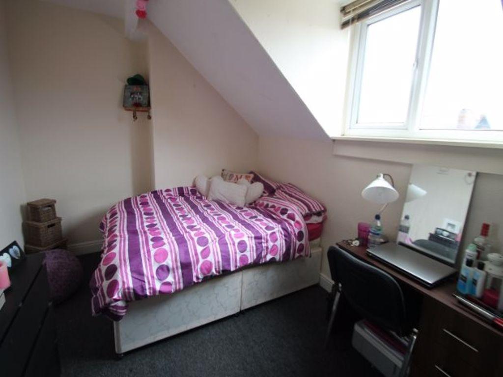 A cozy single bedroom with a purple patterned b...