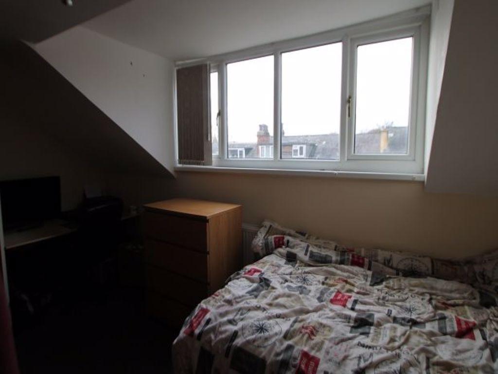 A cozy single bedroom featuring a bed with a pa...