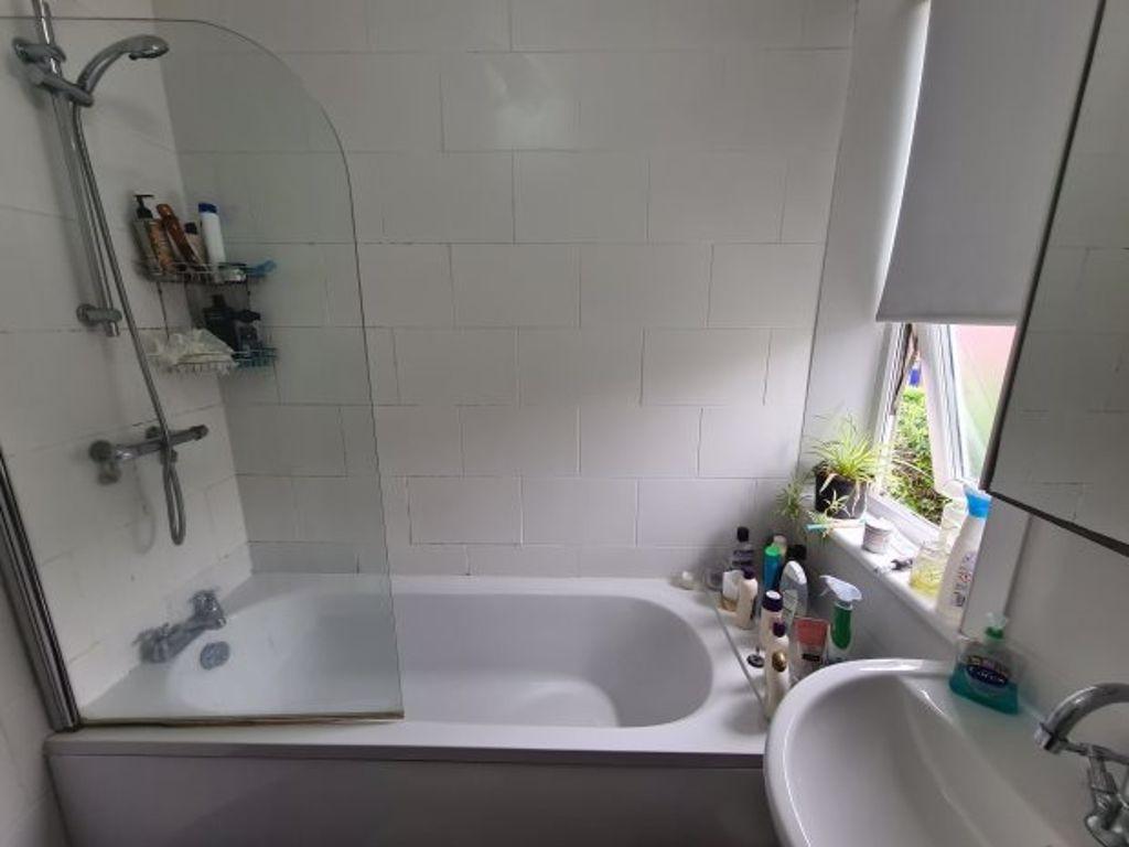 A bright and clean bathroom with a bathtub, fea...