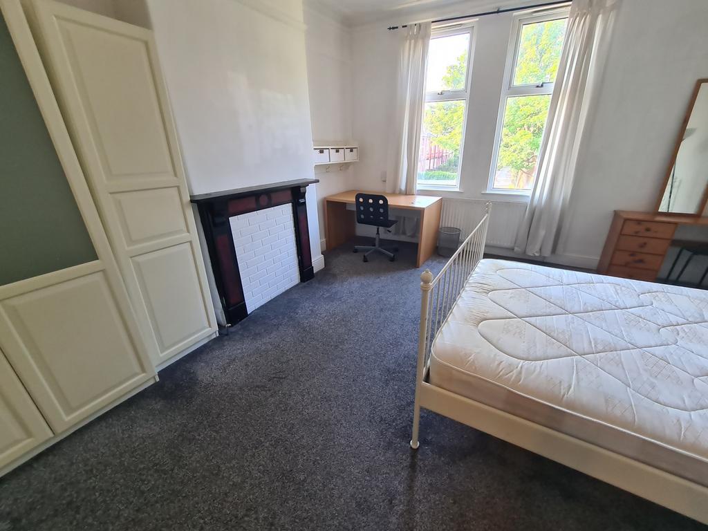 A bright, tidy bedroom featuring large windows ...
