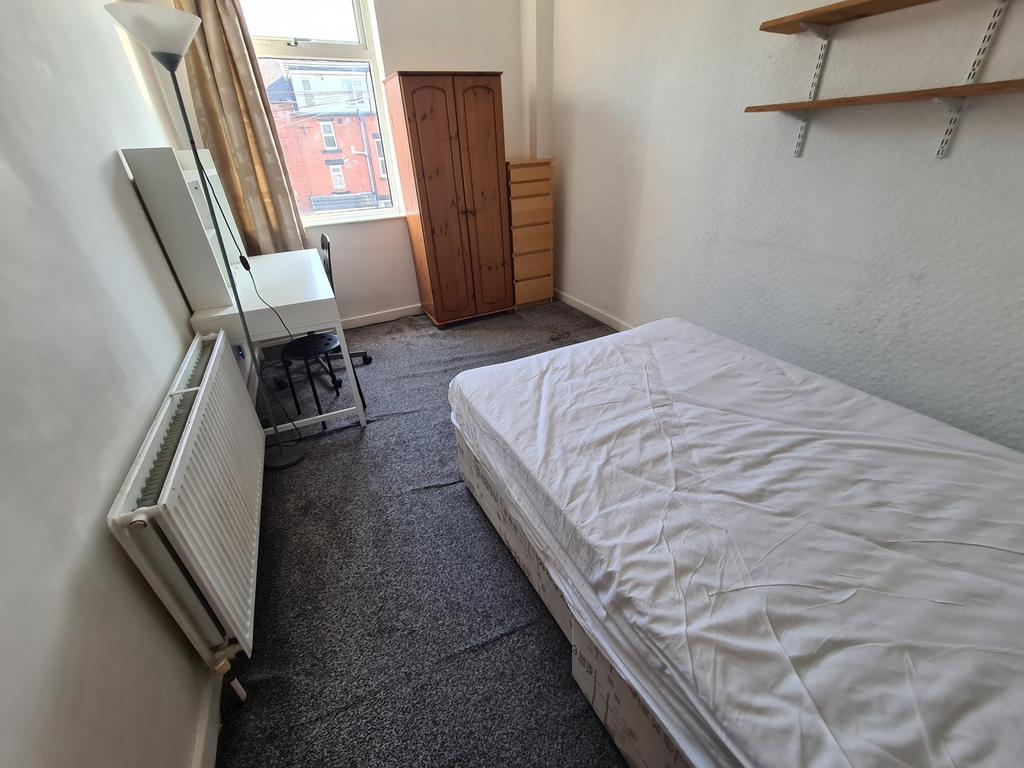 A modest student bedroom featuring a single bed...