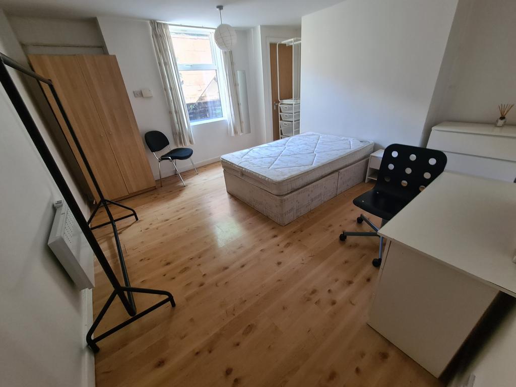 A bright, tidy bedroom featuring a single bed, ...