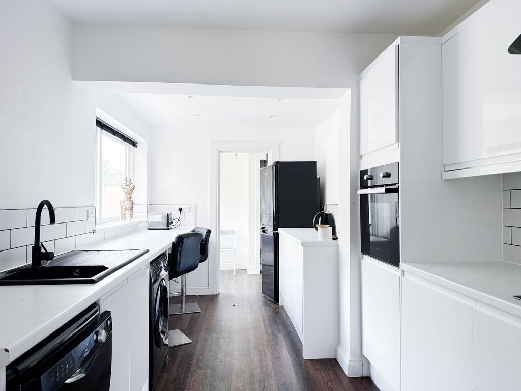 Bright, modern galley kitchen with white cabine...